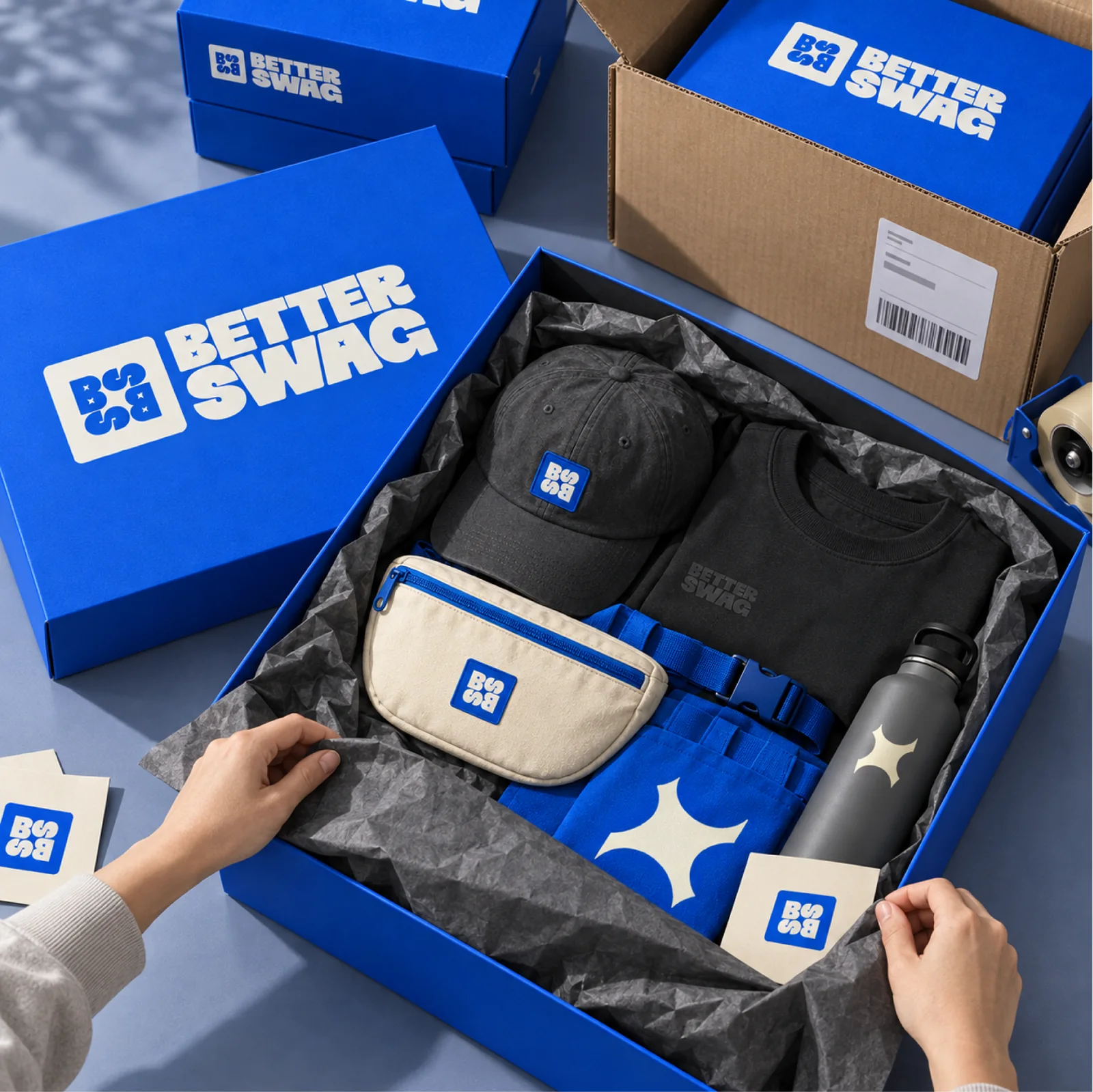 Hands packing a Better Swag box with a cap, fanny pack, tee, and bottle for shipping